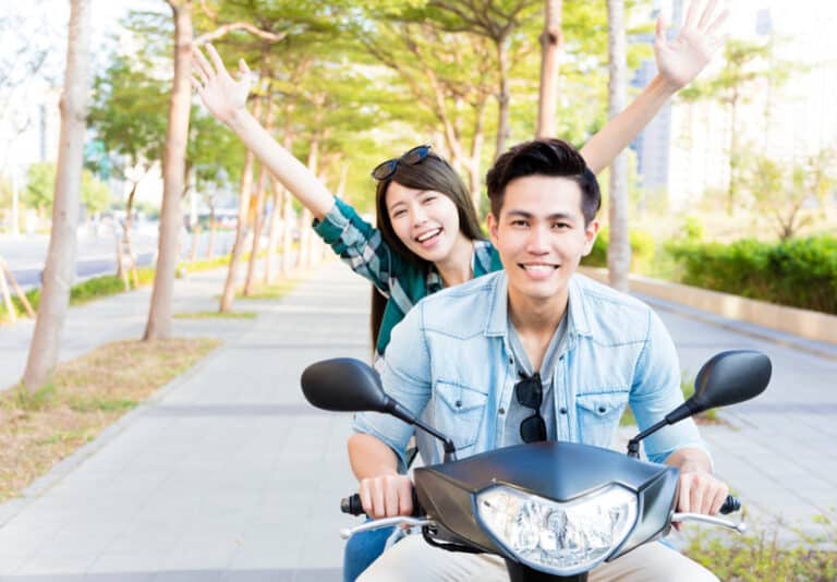 happy young couple riding scooter in town