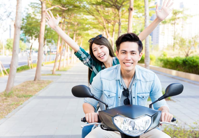 happy young couple riding scooter in town